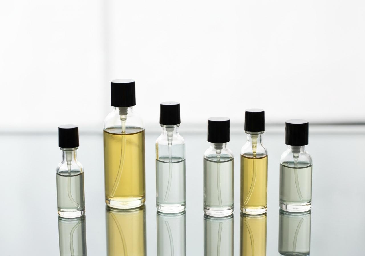 Flacons de parfum sur surface en verre, lumière naturelle douce