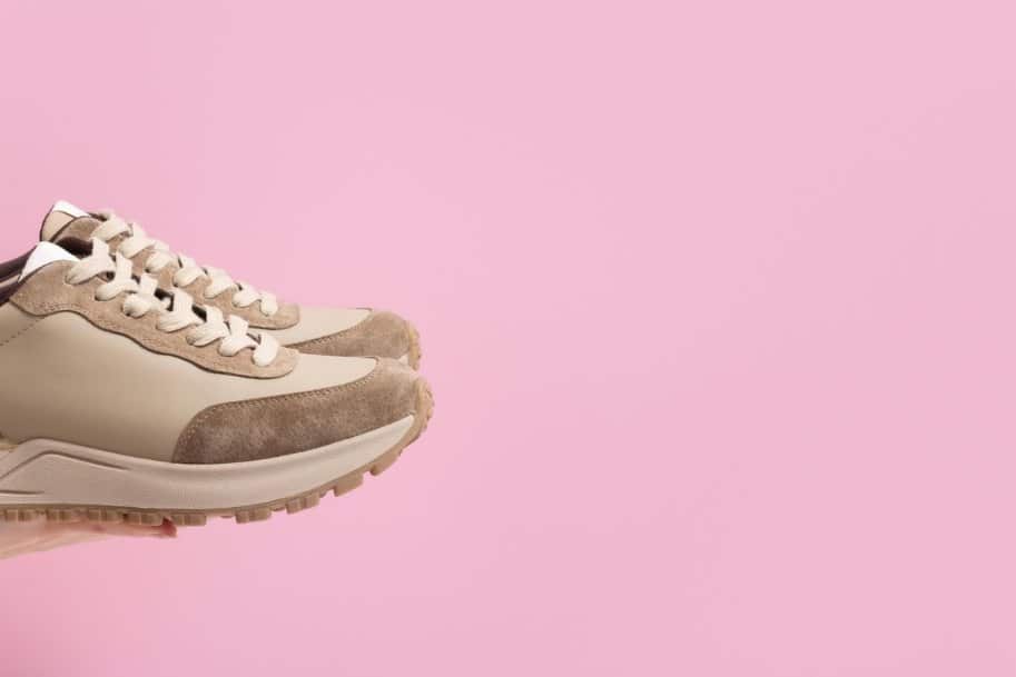 Baskets en cuir pour femmes beiges à la main sur fond rose