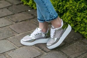 Pieds en baskets argentées sur pavés